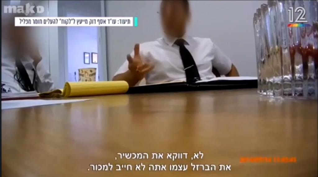 אסף דוק יושב ליד שולחן ומסביר דברים על אבי דביצקי